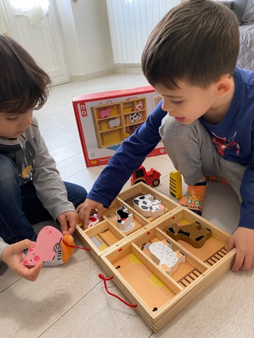 Two children sharing a wooden imaginative play set
