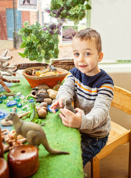 A young child playing with animals in a small-world play scene